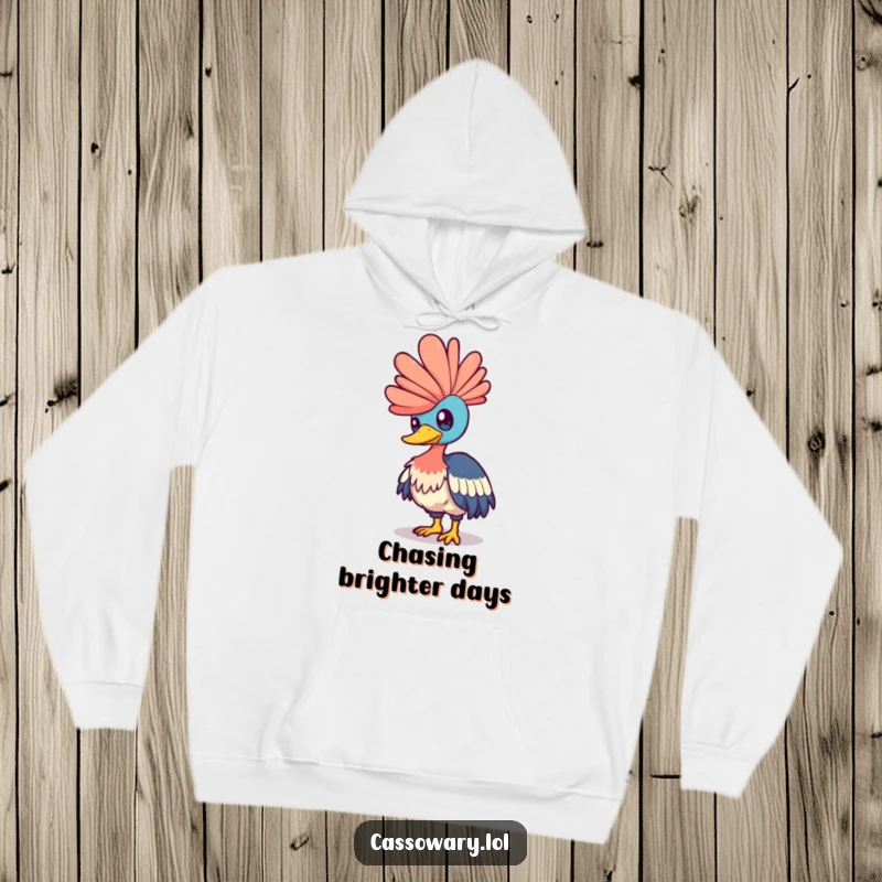 Funny cassowary hoodie showing a bird playfully nudging a shimmering rainbow with its head, designed for cozy enchantment.